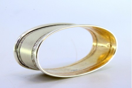 Argola de guardanapo em prata foscada de forma oval e com frisos gregos na envolvência.